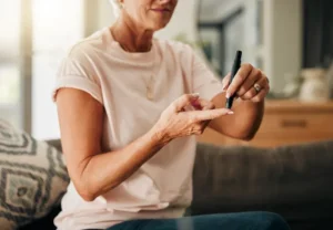 Diabetes health and elderly woman doing a blood sugar test on her finger